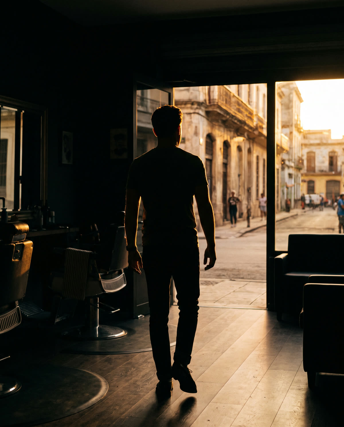 Hombre saliendo del estudio hacia la calle al atardecer, a contraluz
